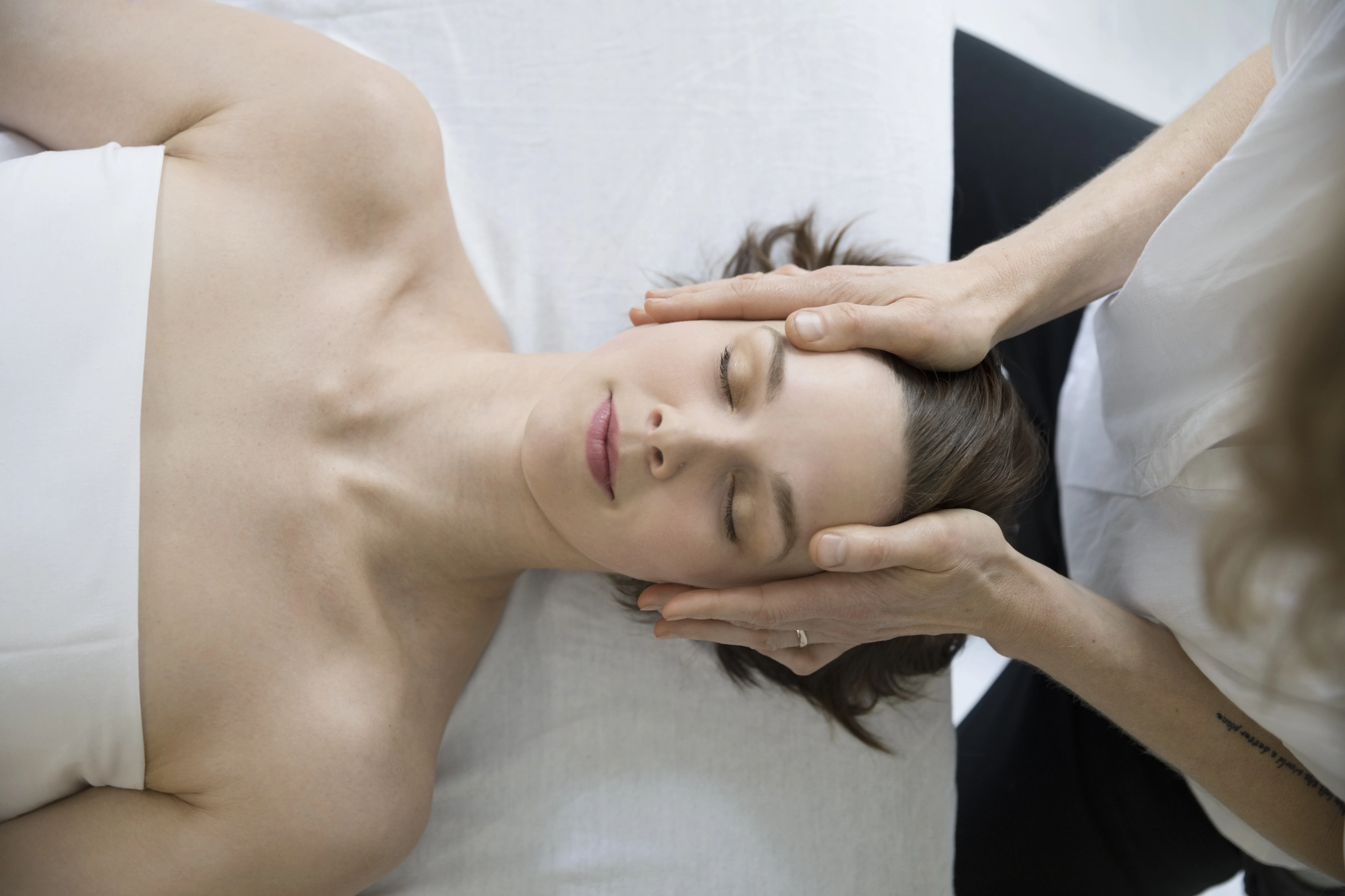 Indian head massage in progress — therapist's hands cradling a reclining client's head