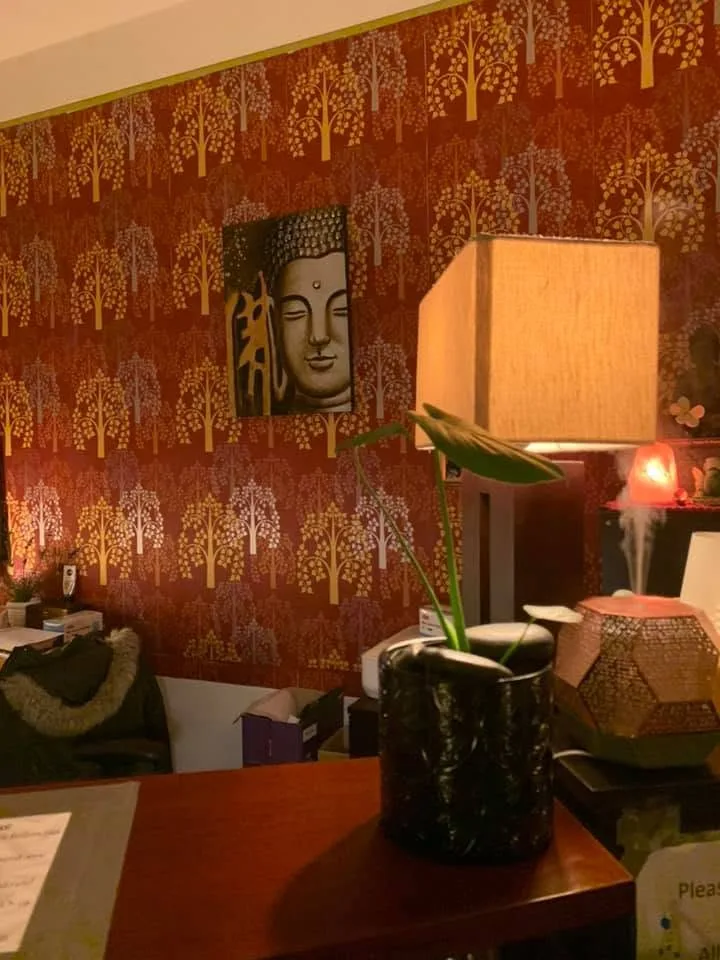 Large Buddha-face canvas on red and gold tree-patterned wallpaper with aroma diffuser releasing steam