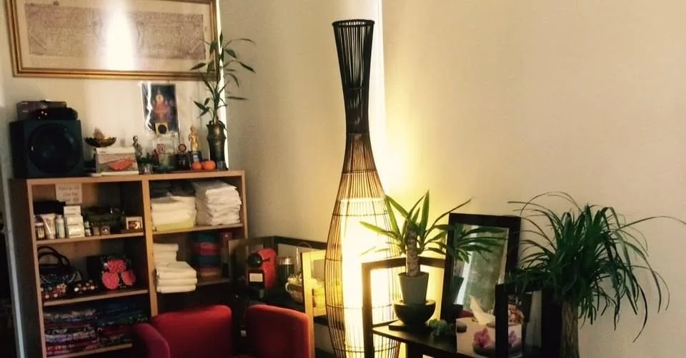 Wide view of the Wanvilai reception — shelves of folded towels, red armchairs, tall woven-rattan floor lamp and plants